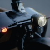 Frontscheinwerfer eines Lastenrades mit zwei kleinen orangenen Lichtern an den Seiten.