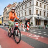 Eine Frau fährt auf einem E-Bike auf einer Radspur durch die Stadt.
