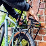 Eine Person montiert einen Gepäckträger mit Schnellverschlüssen an einem Fahrrad.