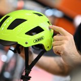 Eine Person präsentiert einen Fahrradhelm in Neongelb.