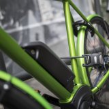 Ein grünes E-Bike, mit einem Faltschloss angeschlossen.