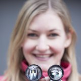 Eine Frau hält zwei Fahrradscheinwerfer vor sich.