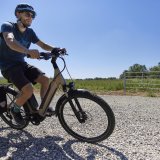 Ein Radfahrer fährt mit einem E-Bike über einen Schotterweg auf dem Land.