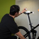 Eine Person misst die Sattelhöhe eines Fahrrades mit einem Maßband.