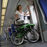 Eine Frau mit einem zusammengeklappten Liegerad in einem Zug.