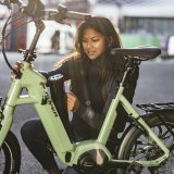 Eine Frau platziert den Akku eines E-Bikes im Rahmen.