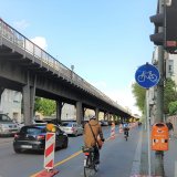 Eine Person fährt mit einem Fahrrad auf einem Bereich einer Straße, der mit Leitbaken von Autospuren getrennt ist.
