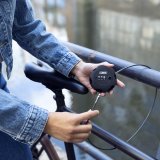 Eine Person schließt ein Fahrrad mit einem dünnen Stahlseil an einem Geländer an.