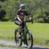 Eine Frau fährt mit einem Fahrrad auf einen Feldweg.