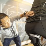 Ein Mann betrachtet, wie eine andere Person auf einem Sattel sitzt.