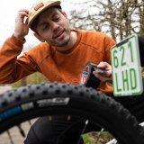 Mann versucht Kennzeichen an Kinderrad anzubringen.