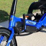 Kurbel mit Motor und Akku am Rahmen eines Liegedreirads.