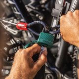 Eine Person schließt mit einem Vorhängeschloss zwei Schlaufen am Ende eines ummantelten Stahlseils zusammen.