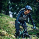 Frau fährt mit Mountainbike über Wiese.