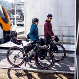 Zwei Personen schieben Fahrräder mit Gepäck daran von einem Zug weg.