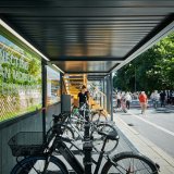 In einem einseitig offenen Metallcontainer stehen mehrere Fahrräder an Haltevorrichtungen.