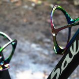 Zwei Flaschenhalter in schillernd bunten Farben, montiert in einem Fahrradrahmen.