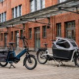 Zwei Lastenräder vor einem Gebäude mit Ziegelfassade.