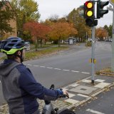 Ein Radfahrer steht an einer Ampel, die gerade umschaltet.