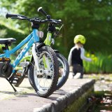 Zwei Kinderräder, die an einer Betonkante über einem Gewässer abgestellt sind.