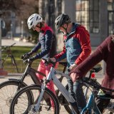 Drei Personen stehen mit E-Bikes auf einem Platz und schauen auf die Bedienelemente am Lenker.