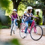 Drei Kinder fahren in einem Park Fahrrad.