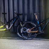 Zwei E-Mountainbikes lehnen an einer Metallwand.