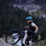 Eine Frau fährt auf einem E-MTB eine steile Felsflanke im Gebirge hinauf.