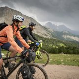 Zwei Personen im Gebirge auf Gravelbikes mit Taschen daran.