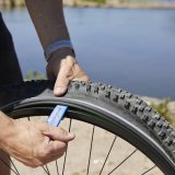 Detailaufnahme von der Benutzung eines Reifenhebers, um einen Fahrradreifen von der Felge zu demontieren.