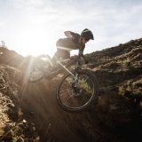 Eine Person springt auf einem Mountainbike eine Böschung runter.