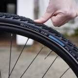 Eine Person drückt mit dem Daumen einen Fahrradreifen etwas ein.