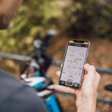 Blick über die Schulter einer Person, die ein Smartphone mit einer Karten-App vor sich hält.