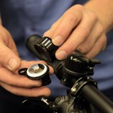 Eine Person zeigt ein Apple Airtag im Inneren einer demontierten Fahrradklingel.