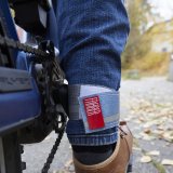 Ein Klettband sichert den Hosenbund einer radfahrenden Person vor der Kette und dem Kettenblatt direkt daneben.