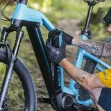 Ein Mann baut den integrierten Akku aus dem Rahmen eines E-Bikes aus.