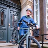 Eine Frau trägt ein Fahrrad die Treppe vor einer Haustür hinab.