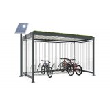 Ein überdachter Fahrradstellplatz mit Grünfläche auf dem Dach und einer Solarzelle daneben.