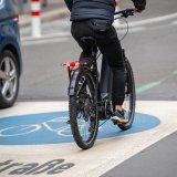 Eine Person fährt auf einem E-Bike über die Fahrbahnmarkierung einer Fahrradstraße.