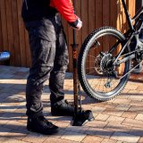 Eine Person pumpt mit einer Standpumpe den Hinterreifen eines E-Mountainbikes auf.