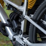 Eine Person hantiert am Akku im Rahmen eines E-Mountainbikes.