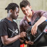 Zwei Männer arbeiten an einer unfertigen Fahrradtasche.