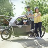 Familie mit Lastenrad auf Spielplatz