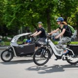Zwei Personen auf Lastenrädern fahren nebeneinander.
