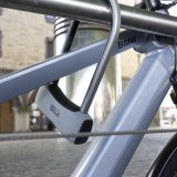 Ein Bügelschloss sichert ein Fahrrad mit dem Rahmen an einem Geländer.