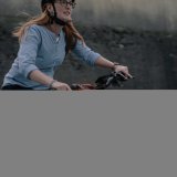 Eine Frau fährt in der Dämmerung ein E-Bike. An der rechten Seite des Lenkers ist ein orangefarbenes Licht zu sehen.