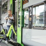 Eine Frei steigt mit einem E-Bike mit kleinen Rädern in einen Zug ein.