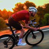 Ein Mann fährt auf einem Rennrad vor der tief stehenden Sonne eine Straße entlang.