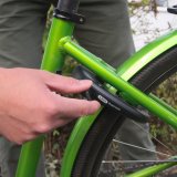 Eine Person hantiert am Schlüssel eines Rahmenschlosses an einem grünen Fahrrad.