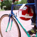 Ein roter Ball, mit Hilfe eines weißen Bandes im Rahmen eines Fahrrades befestigt.